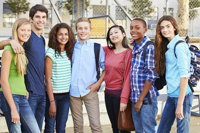 Group of diverse, young teenage students, standing in a group as friends and peers