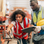 Two people in a factory looking at a machine.