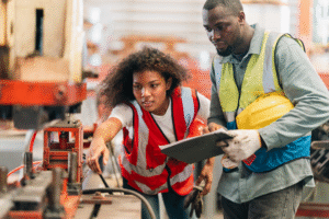 Two people in a factory looking at a machine.